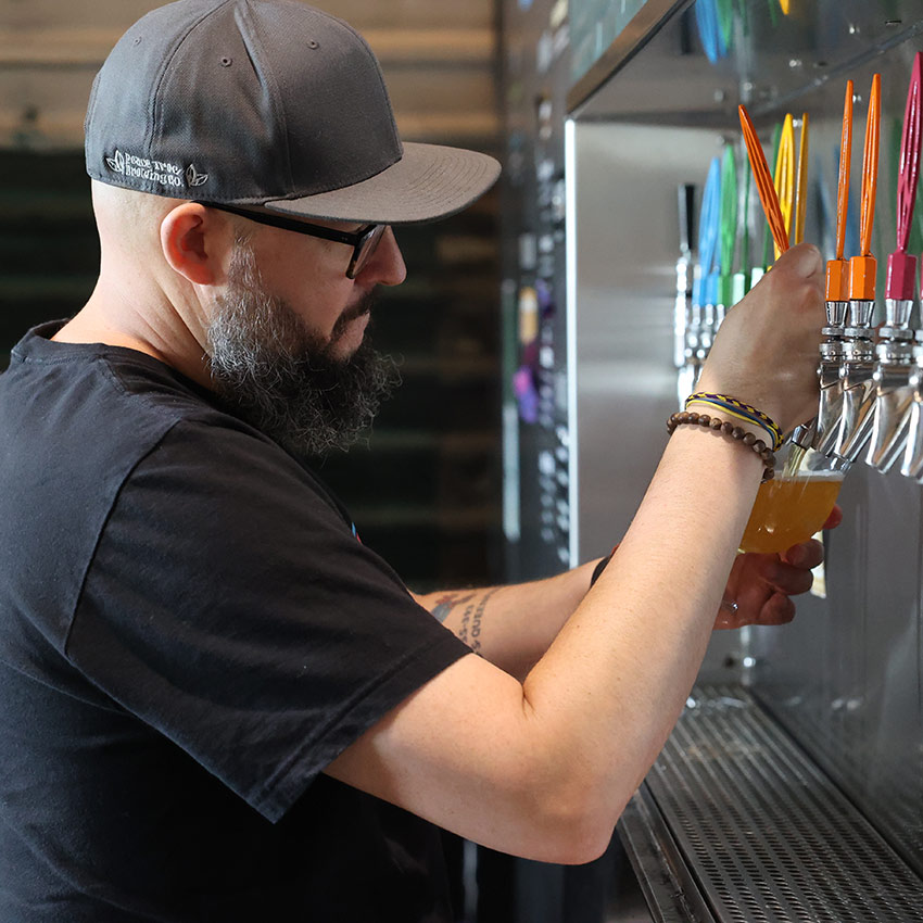 a person pouring a beer from a beer tap